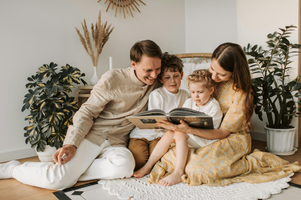 A happy young family with two kids reading together at home.