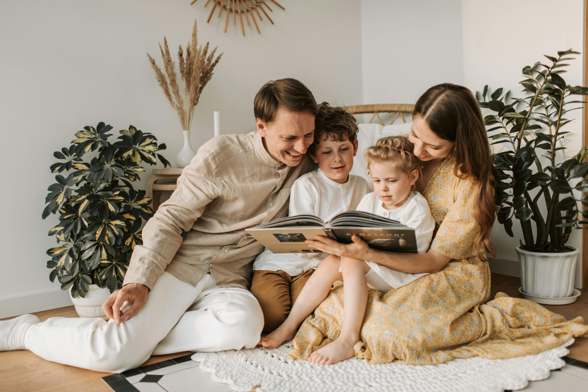 A happy young family with two kids reading together at home.